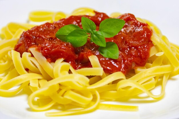 Foto pasta tradicional de tagliarini con salchicha de tomate y queso parmesano