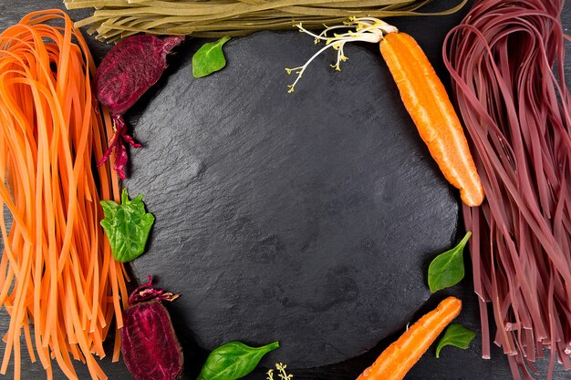 Foto pasta vegetal vegetariana de color crudo con remolachas, zanahorias y espinacas.