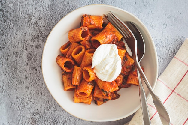 Foto pasta vegetariana con salsa de tomate y requesón en cuenco blanco de fondo gris