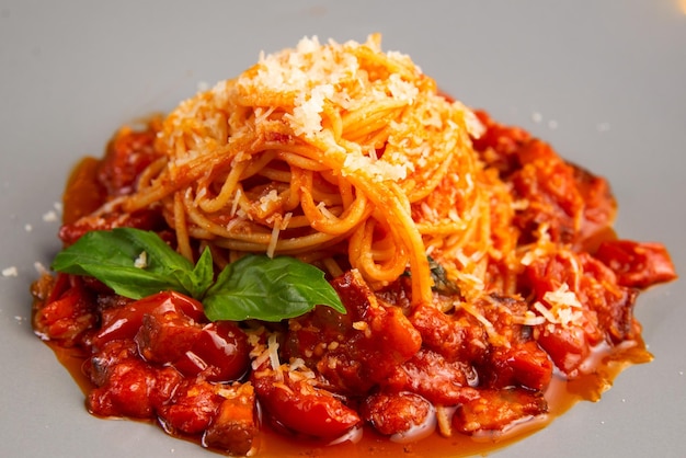 Pasta vegetariana con salsa de tomate rojo parmesano y albahaca en un plato blanco