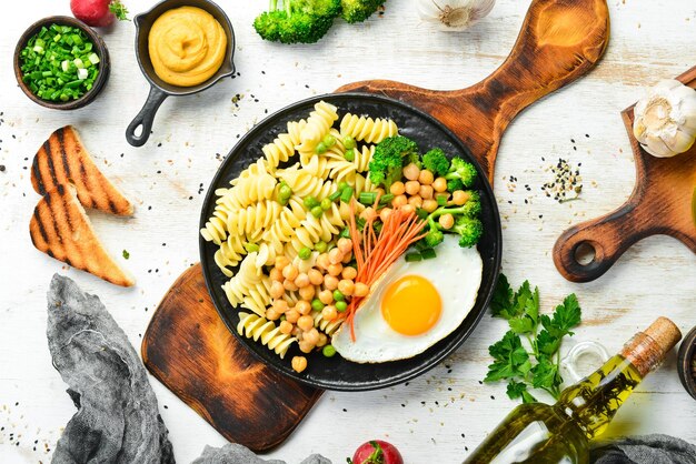 Pasta con verduras y huevo frito en un plato de piedra negra Bowl Buddha Vista superior Espacio libre para texto