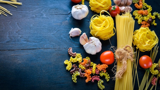 Pasta con verduras, tomates cherry, chiles y ajo Sobre un fondo de madera Espacio libre para texto Vista superior