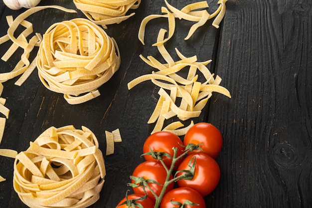 Pasta Zutaten Tagliatelle mit italienischen Zutaten Set, auf schwarzem Holztisch Hintergrund, mit Kopierraum für Text