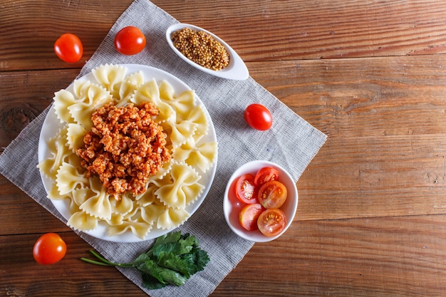 Pastas boloñesas de Farfalle con la carne picadita en de madera marrón.