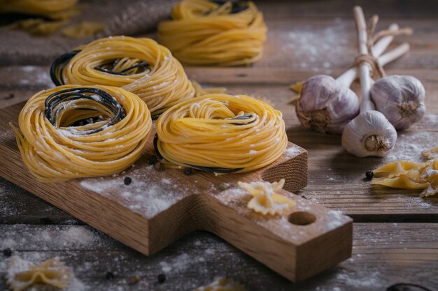 Pastas caseras crudas con harina, ajo y especias en el fondo rústico. Fideos crudos.