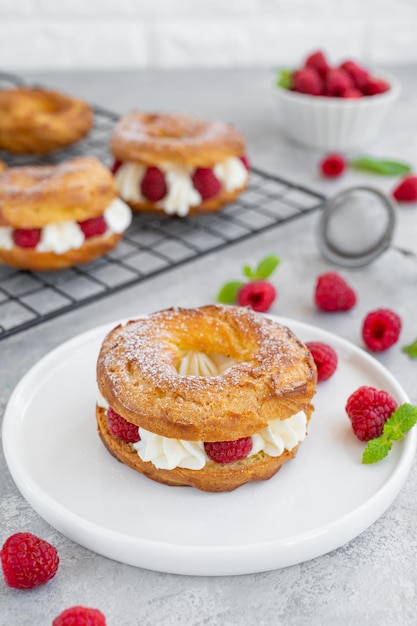 Pastas choux Aros de choux con crema de queso crema y frambuesas espolvoreadas con azúcar glas