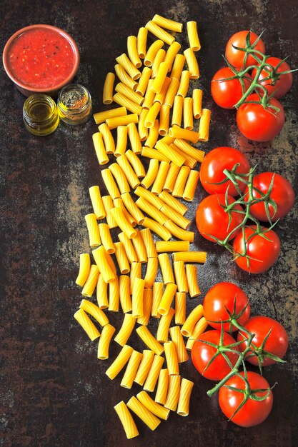 Pastas crudas y tomates en la rama. Concepto de cocina pasta con salsa de tomate.