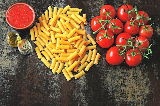 Pastas crudas y tomates en la rama. Concepto de cocina pasta con salsa de tomate.