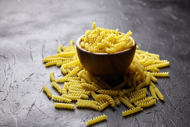 Pastas Girandole en cuenco de madera sobre mesa de piedra negra