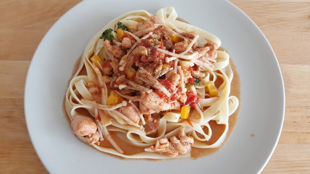 Pastas hechas en casa del pollo servidas en la tabla de madera.