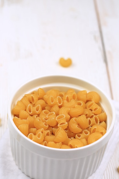 Pastas secas crudas sobre un fondo de madera blanco