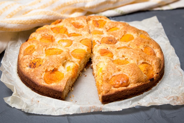 Pastel de albaricoque en el papel de hornear con albaricoques maduros