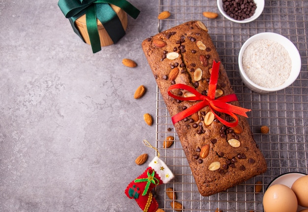 Pastel de almendras con chispas de chocolate con adornos navideños sobre fondo gris