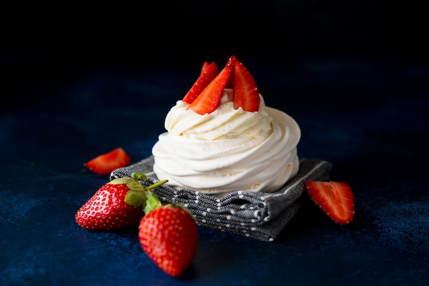 Pastel de Anna Pavlova con crema y fresas frescas sobre un fondo oscuro, cerrar