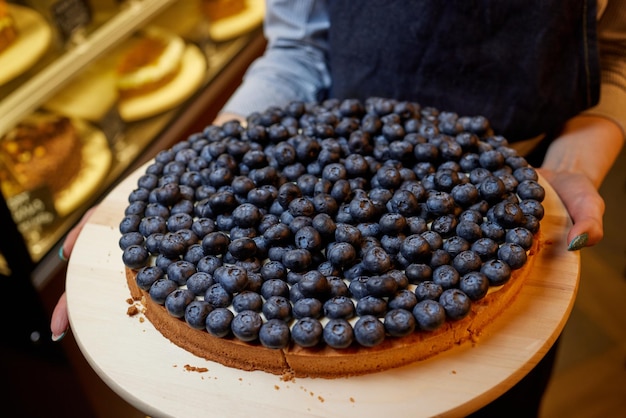 Pastel de arándanos de tamaño individual recién horneado en un plato vintage con bayas frescas. Mesa de madera rústica como fondo. Primer plano desde arriba con iluminación direccional natural.