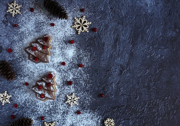 Pastel de árbol de Navidad con copos de nieve de bayas y azúcar en polvo sobre un fondo oscuro