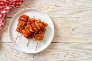 Foto pastel de arroz coreano frito (tteokbokki) ensartado con salsa picante - estilo de comida coreana