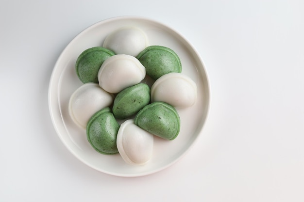 Foto pastel de arroz con forma de media luna de songpyeon de dos colores, servido en el plato blanco