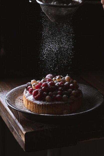 El pastel con bayas está salpicado de azúcar en polvo