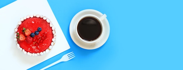 Pastel de bayas pequeñas y una taza de café vista superior fondo azul Dulzura