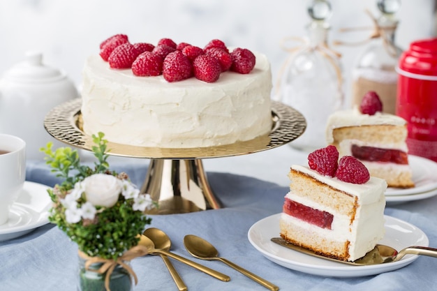 Pastel blanco con una corona de frambuesas en el fondo blanco.