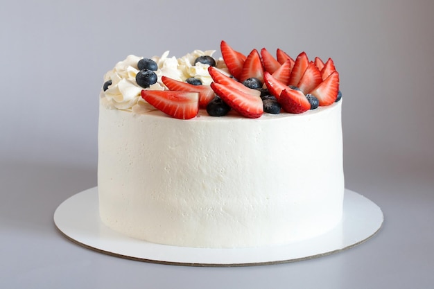 Pastel blanco con fresas maduras y postre de arándanos