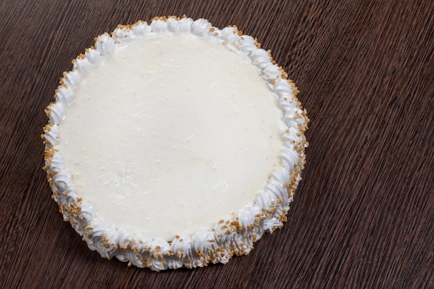 Pastel blanco grande con una tapa en blanco sobre una mesa de madera