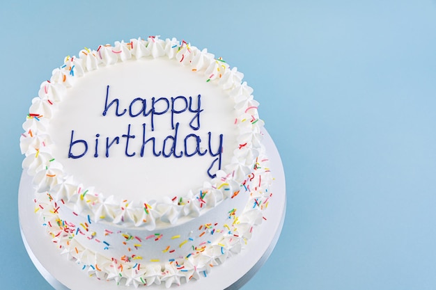 Foto pastel blanco con la inscripción feliz cumpleaños en la vista superior de fondo azul