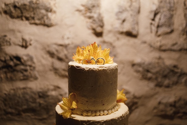 Pastel de boda blanco sobre un fondo de pared de piedra