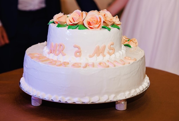 El pastel de bodas blanco adornado con delicadas rosas marca el final de la ceremonia simbolizando su dulce viaje hacia adelante novio y novia