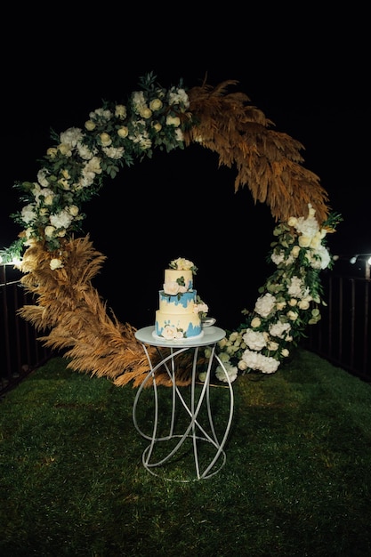 Pastel de bodas en la boda por la noche en el fondo del arco