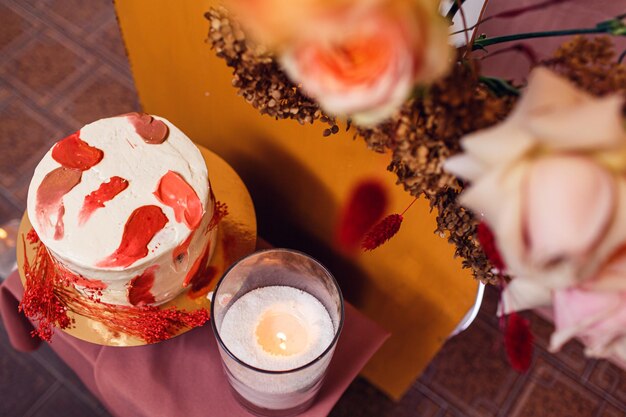 Pastel de bodas cerca del arco de bodas con flores.