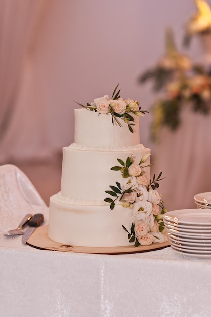 Foto el pastel de bodas en colores delicados y platos blancos están en la mesa banquet 2672