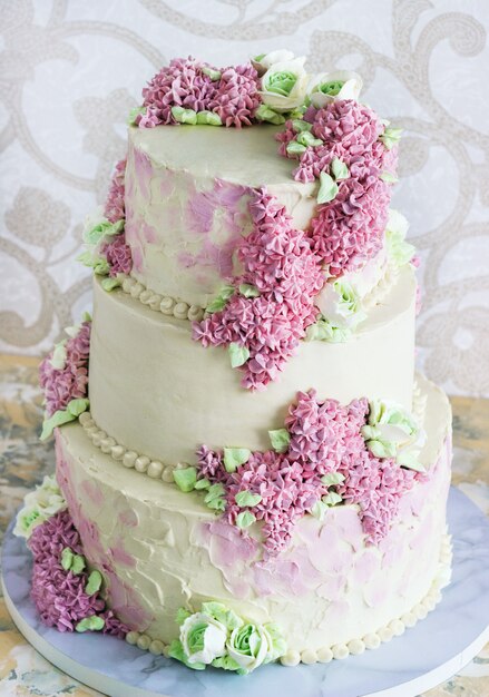 Pastel de bodas festivas con flores de color lila sobre fondo blanco.