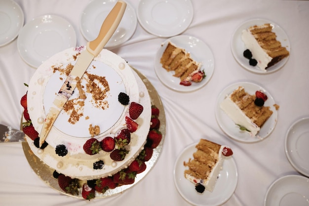 Pastel de bodas festivo cortado en pedazos con un cuchillo