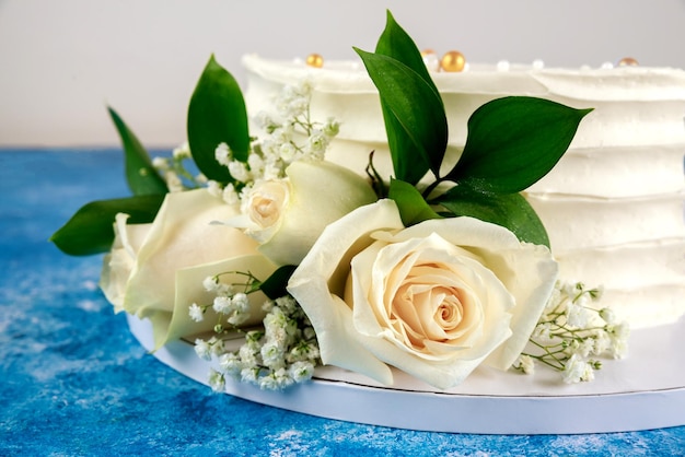 Pastel de bodas con rosas blancas sobre fondo azul. De cerca.