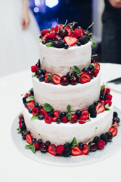 Pastel de bodas de tres capas con bayas frescas. Decorado con fresas, arándanos, cerezas y moras.