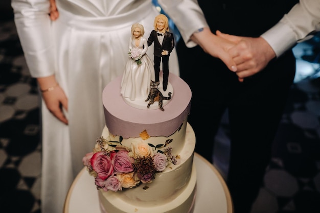 Pastel de bodas de tres niveles con figuras de personas en él