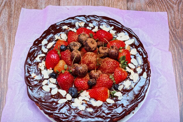 Pastel de brownie decorado con frutos rojos sobre mesa de madera