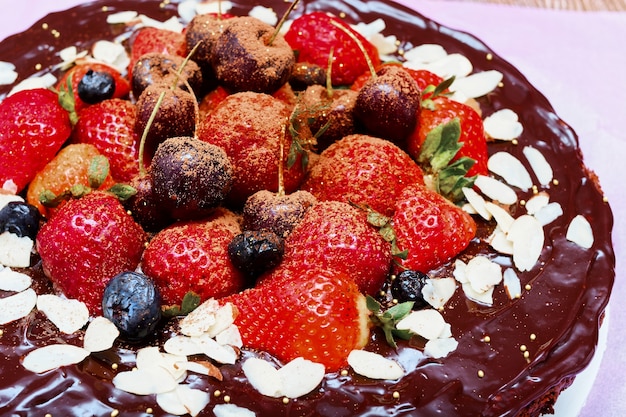 Pastel de brownie decorado con frutos rojos sobre mesa de madera