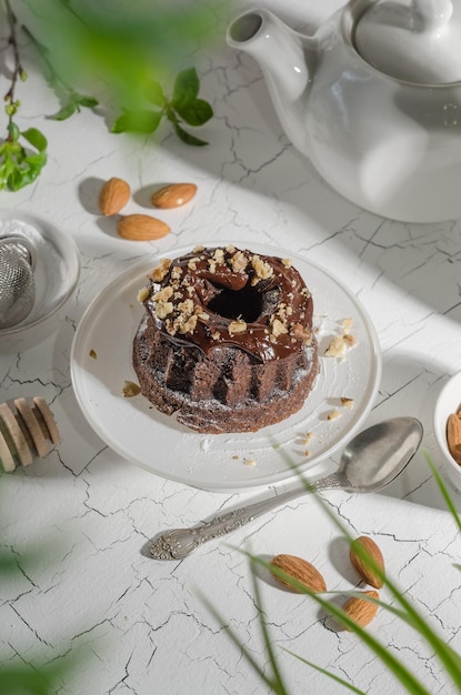 Pastel de brownie vertido con chocolate y nueces en un soporte blanco con luz dura