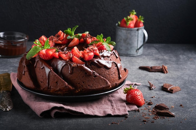 Pastel Bundt de chocolate oscuro con glaseado Ganache y fresa sobre piedra oscura o fondo de mesa de hormigón Pastel festivo Enfoque selectivo