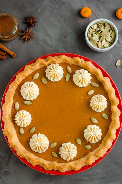 Pastel de calabaza tradicional con crema batida de especias y semillas en la parte superior Postre para el Día de Acción de Gracias