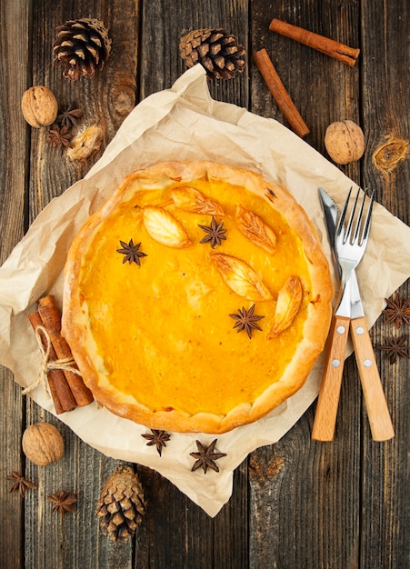 Pastel de calabaza tradicional en una mesa de madera en hojas de otoño. Primer plano, vista superior.