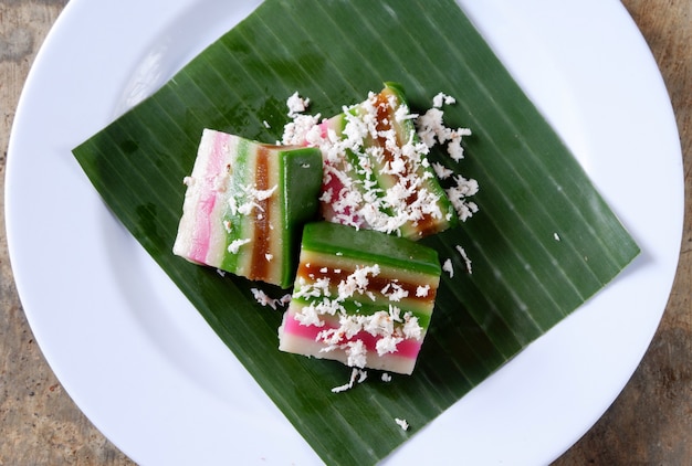 Pastel de capas y coco rallado en un plato con hoja de plátano, comida malaya