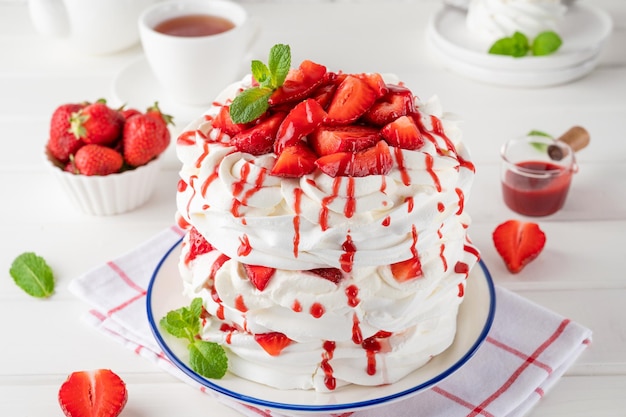 Pastel en capas Pavlova con salsa de fresas frescas y crema batida Hermoso pastel de verano