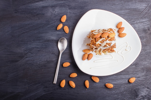 Pastel con caramelo, salsa de leche blanca y almendras en un plato blanco