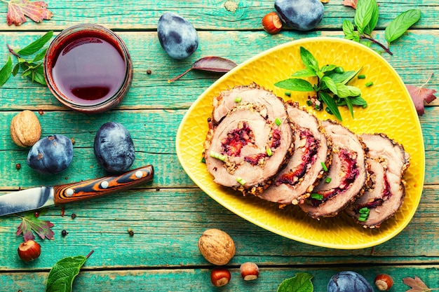 Pastel de carne o rollo de carne al horno con ciruela de otoño sobre fondo de madera rural