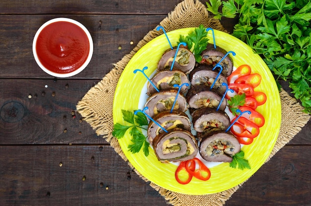 Pastel de carne (rollo) con diferentes rellenos (espinacas, queso, champiñones), cortado en trozos en un plato de cerámica con pimiento dulce. Plato de carne festivo.