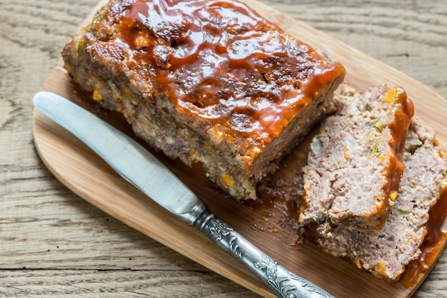 Pastel de carne con salsa barbacoa sobre la plancha de madera